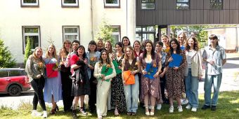 Abschlusskurs der Ergotherapie, viele junge Menschen, die ihr Zeugnis und eine Rose in der Hand halten und stolz lächeln.