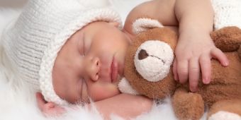 Das Motiv zeigt ein Baby mit Teddy